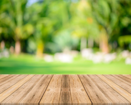 A wooden patio, deck, or outdoor area floor with a green landscape in the background.